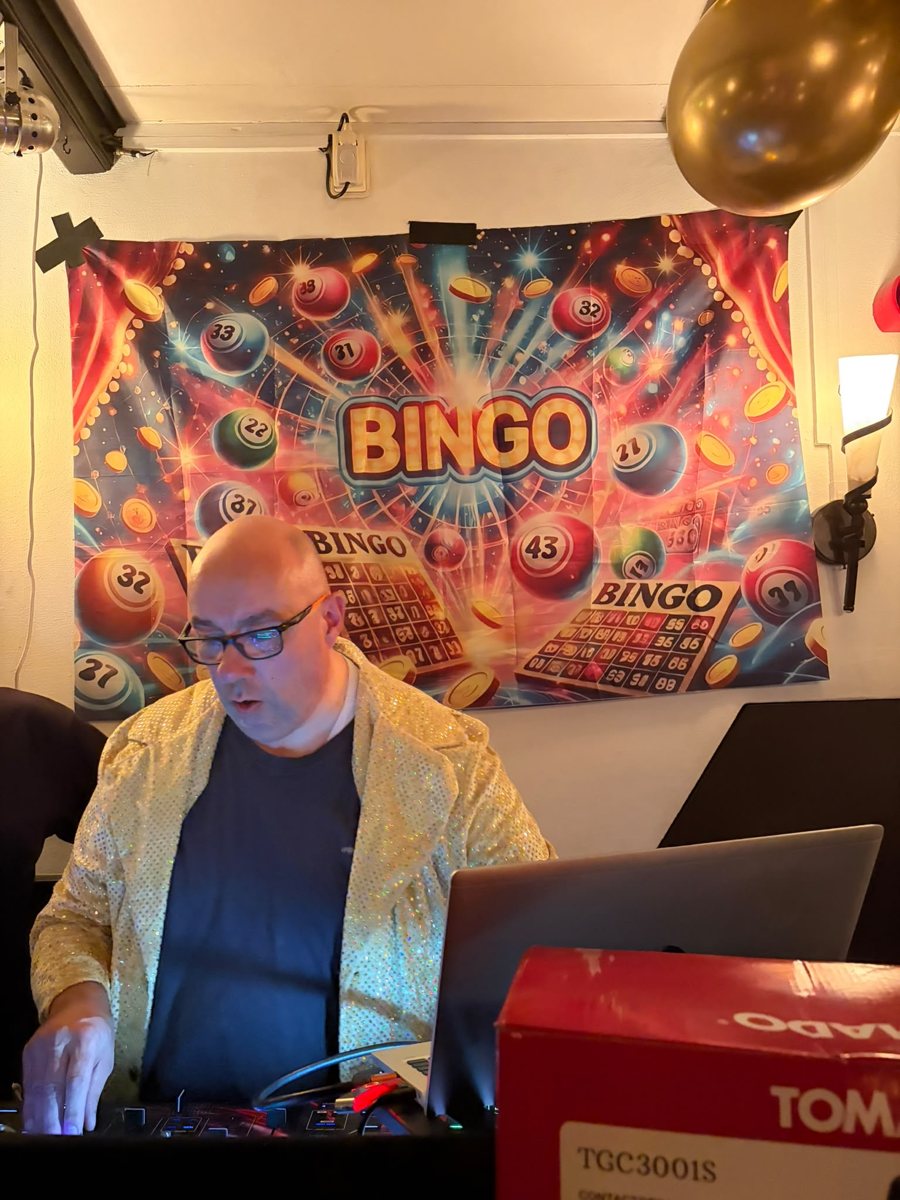 DJ tijdens de muziekbingo met kleurrijke bingobanner